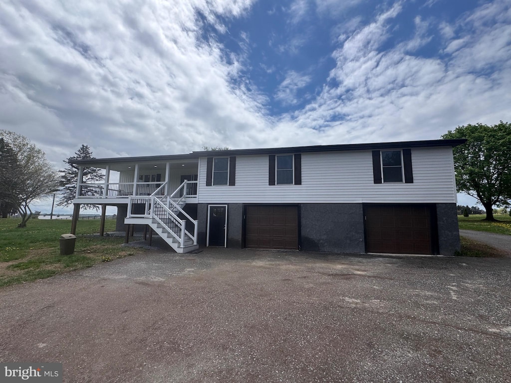 view of front of property featuring an attached garage, driveway, covered porch, and stairway