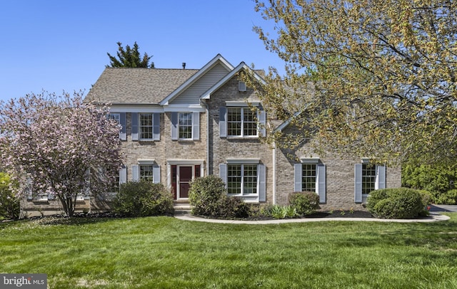 colonial-style house featuring brick siding and a front yard