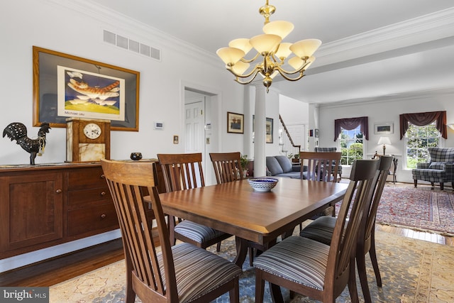 dining area featuring visible vents, ornamental molding, an inviting chandelier, wood finished floors, and stairway