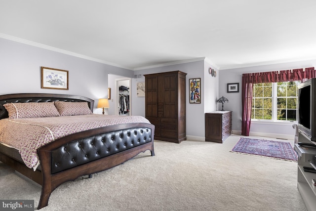 carpeted bedroom featuring crown molding, baseboards, a spacious closet, and a closet