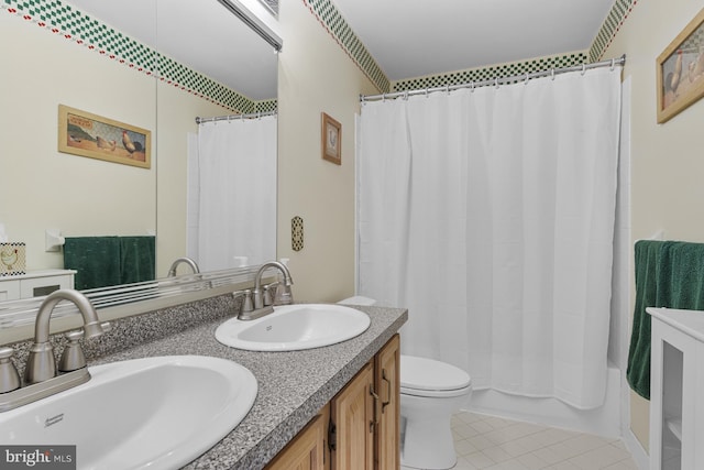 bathroom with a sink, tile patterned floors, toilet, and double vanity