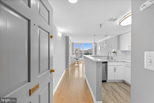 hallway with baseboards, visible vents, a sink, and light wood finished floors