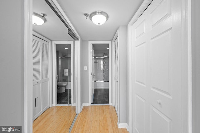 corridor featuring baseboards and light wood finished floors