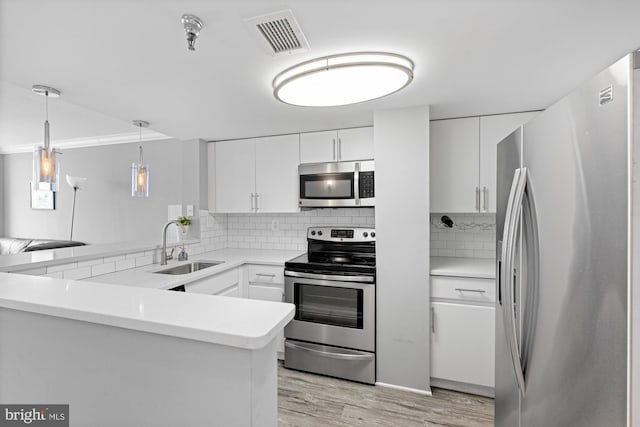 kitchen featuring visible vents, decorative backsplash, a peninsula, a sink, and stainless steel appliances
