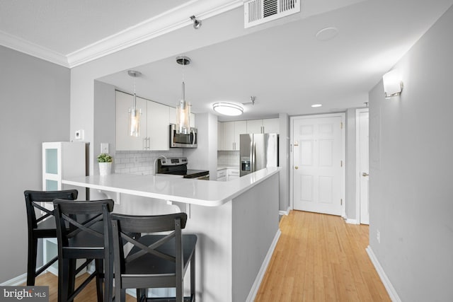 kitchen with white cabinets, light countertops, stainless steel appliances, a peninsula, and tasteful backsplash