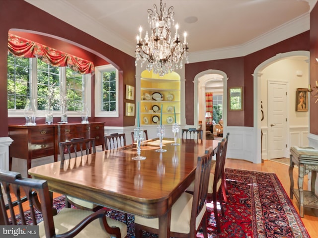 dining area featuring crown molding, arched walkways, and wood finished floors