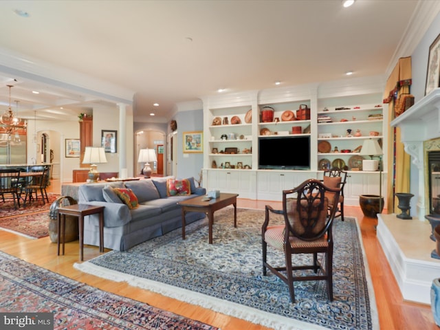 living area featuring crown molding, arched walkways, recessed lighting, wood finished floors, and ornate columns