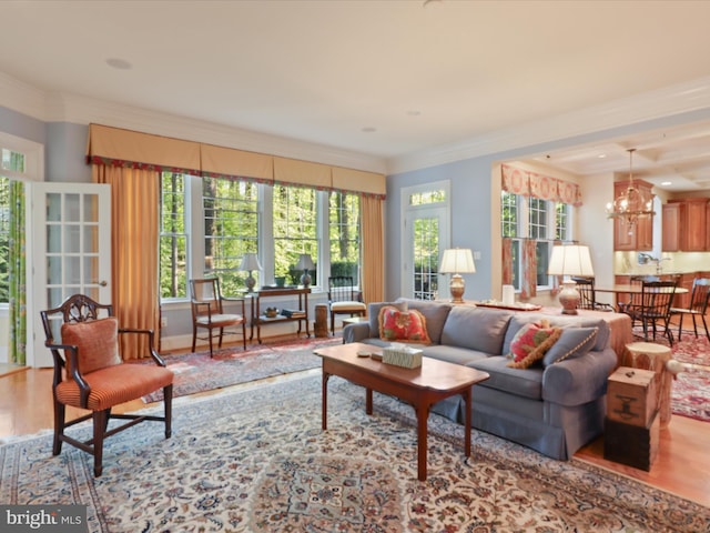 living room with an inviting chandelier, ornamental molding, and wood finished floors