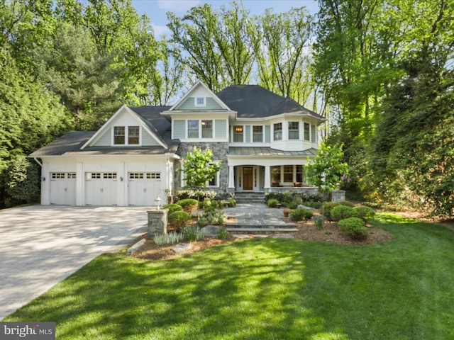 craftsman inspired home featuring covered porch, driveway, a garage, a front lawn, and stone siding