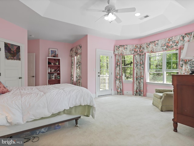 carpeted bedroom featuring a raised ceiling, ceiling fan, access to exterior, and visible vents