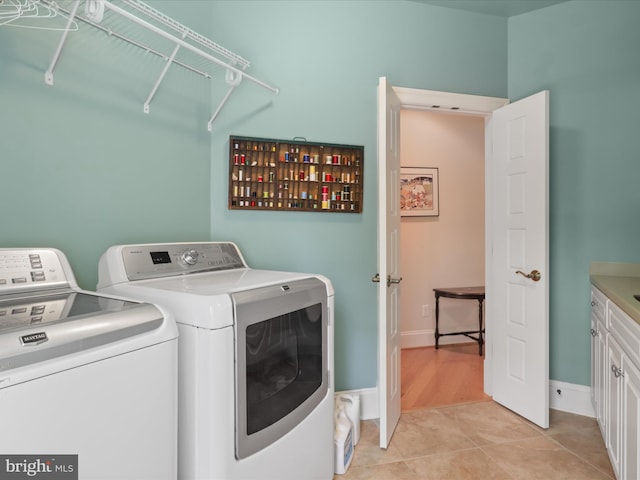 laundry area with cabinet space, separate washer and dryer, baseboards, and light tile patterned floors