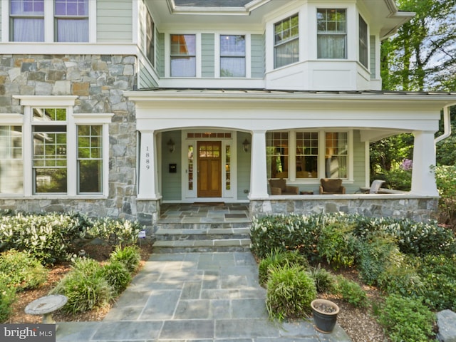 property entrance with a porch and stone siding