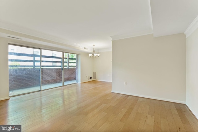 empty room featuring crown molding, light wood-style flooring, and a chandelier