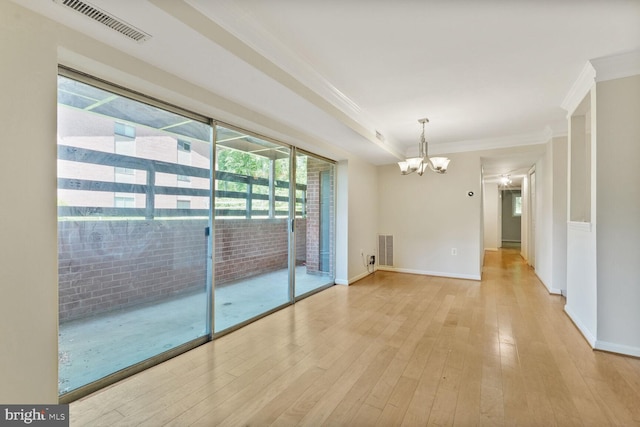 unfurnished room featuring visible vents, ornamental molding, wood-type flooring, baseboards, and a chandelier