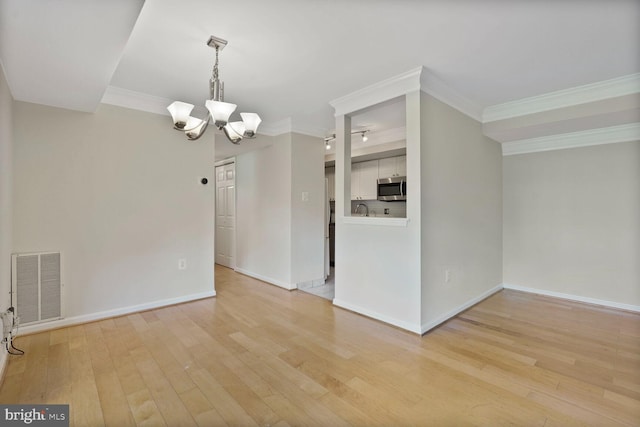 spare room featuring visible vents, ornamental molding, and a notable chandelier