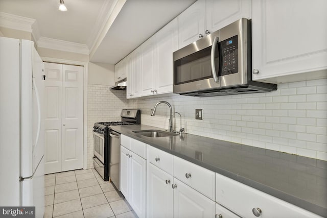 kitchen with crown molding, dark countertops, a sink, stainless steel appliances, and under cabinet range hood