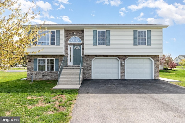 split foyer home with stone siding, aphalt driveway, a front lawn, and a garage