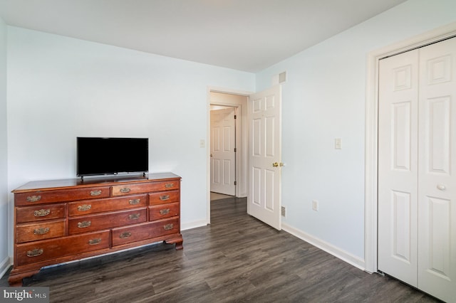 bedroom with dark wood-type flooring, visible vents, baseboards, and a closet