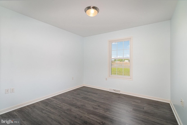 spare room with visible vents, dark wood-style flooring, and baseboards
