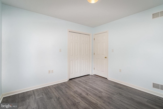 unfurnished bedroom featuring visible vents, a closet, dark wood finished floors, and baseboards