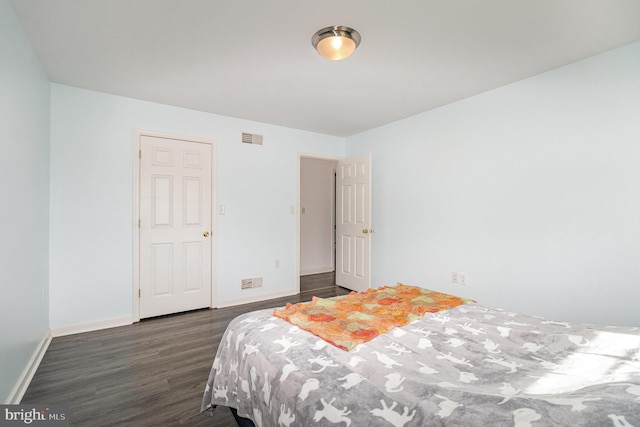 bedroom with dark wood-style floors, visible vents, and baseboards