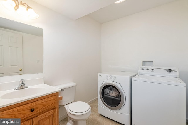 bathroom featuring tile patterned flooring, toilet, vanity, baseboards, and washer and clothes dryer
