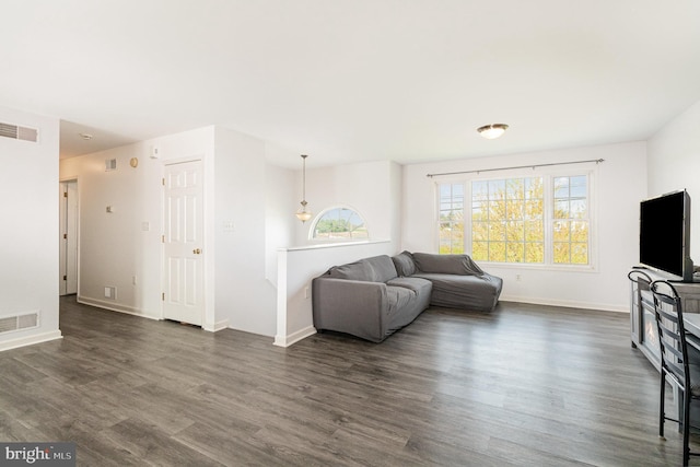 living area with dark wood-style flooring, visible vents, and baseboards