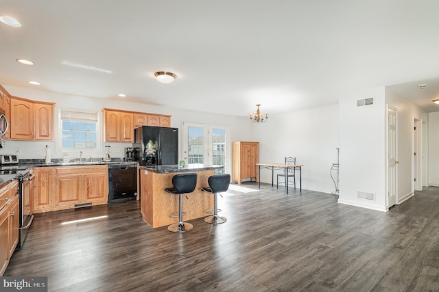 kitchen with a center island, black appliances, visible vents, and dark wood-style flooring