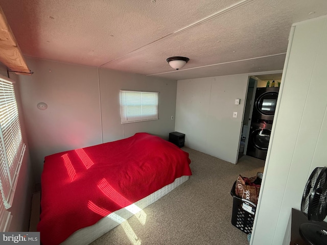 carpeted bedroom featuring a textured ceiling and stacked washer / drying machine