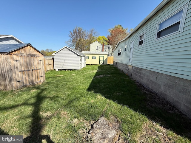 view of yard with fence, an outbuilding, and a shed