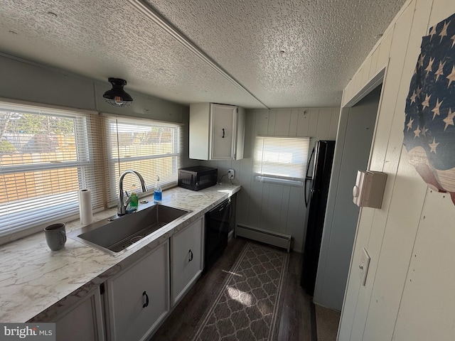 kitchen with a textured ceiling, dark wood finished floors, a sink, black appliances, and a baseboard heating unit