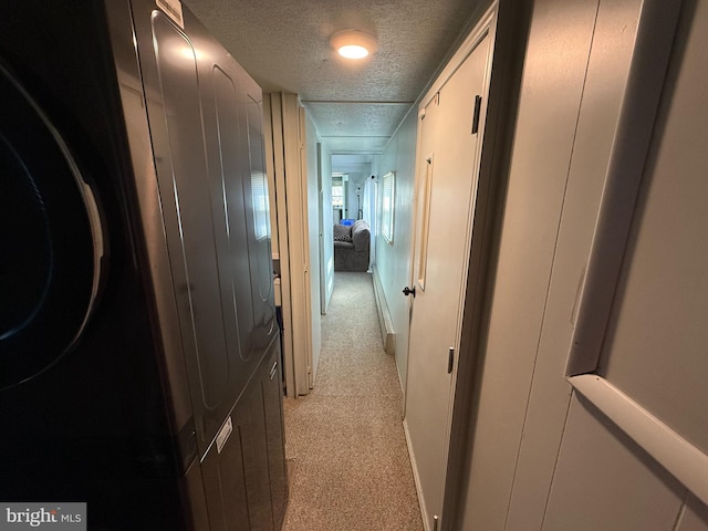 corridor with a textured ceiling, light carpet, and baseboards
