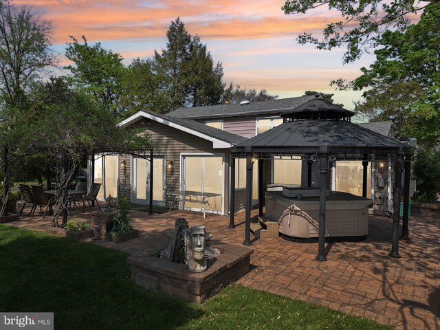 1511 Glenview Dr, Cinnaminson, NJ 08077 - back of house at dusk featuring a hot tub, a gazebo, a patio area, a yard, and a shingled roof