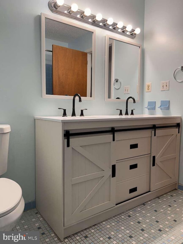 bathroom featuring toilet, double vanity, and a sink