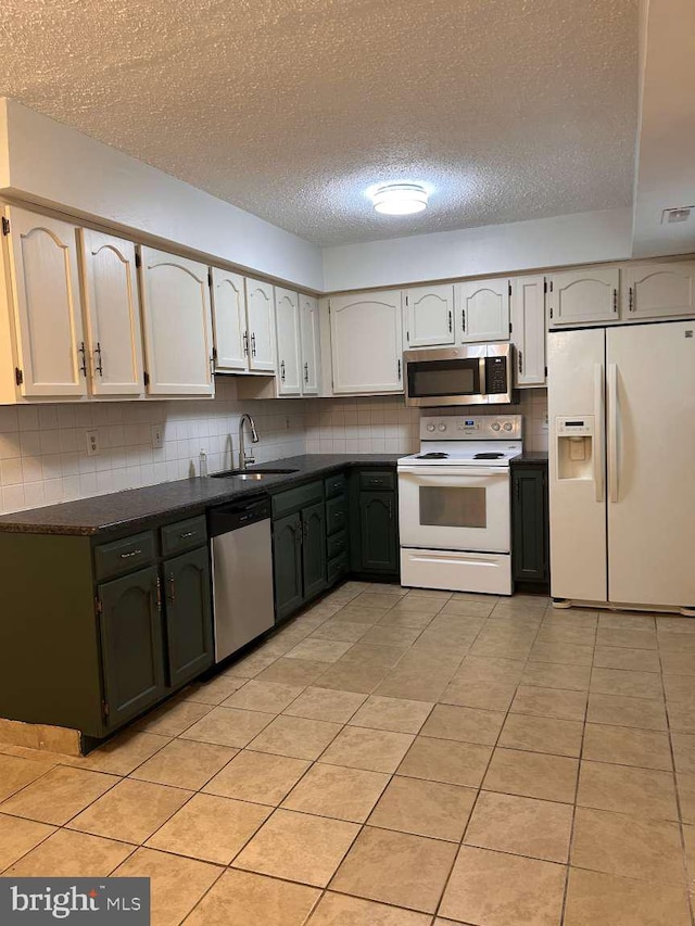 kitchen featuring a textured ceiling, tasteful backsplash, a sink, appliances with stainless steel finishes, and dark countertops