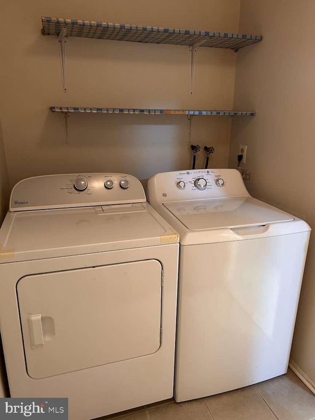 laundry room featuring light tile patterned flooring, washer and clothes dryer, and laundry area