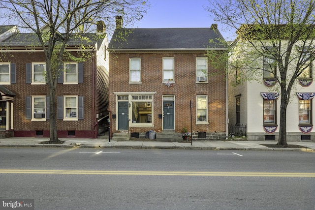 view of property featuring entry steps, a chimney, and brick siding