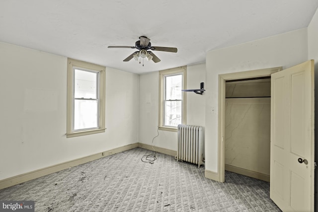 unfurnished bedroom featuring radiator, baseboards, light carpet, and multiple windows