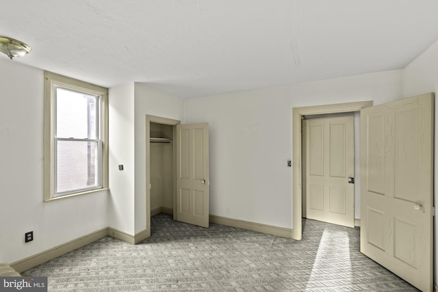 unfurnished bedroom with baseboards, a closet, and light colored carpet