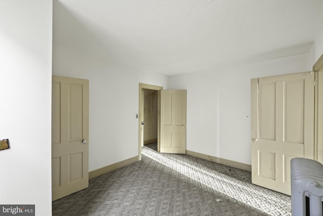 interior space featuring carpet flooring, baseboards, and radiator heating unit