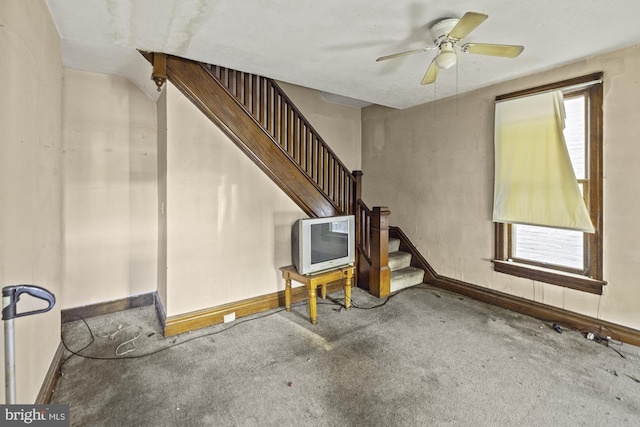 unfurnished living room featuring stairway, carpet floors, baseboards, and a ceiling fan