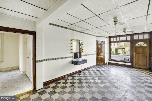 foyer entrance with tile patterned floors, a drop ceiling, and ceiling fan