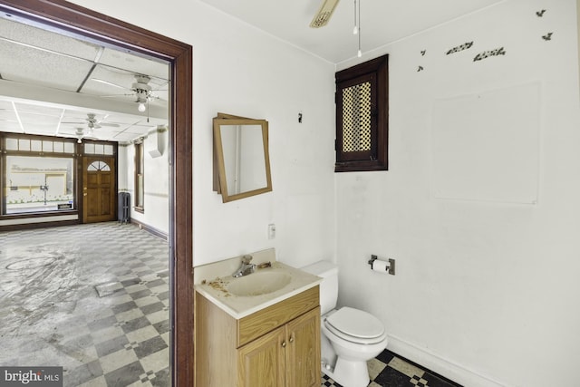 bathroom featuring vanity, toilet, baseboards, tile patterned floors, and a ceiling fan