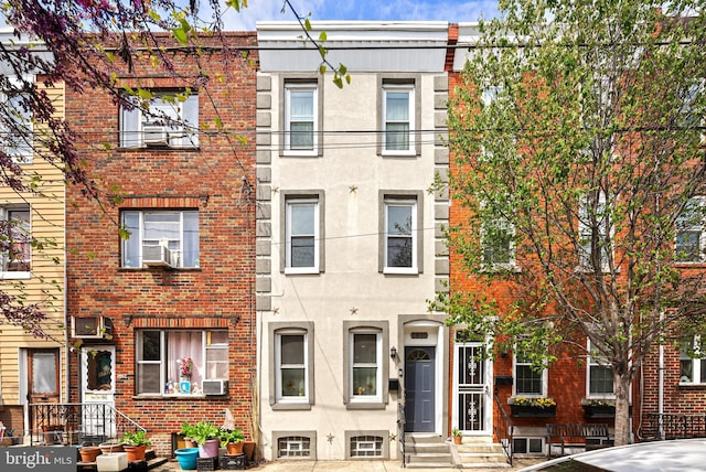 townhome / multi-family property with cooling unit, entry steps, and brick siding