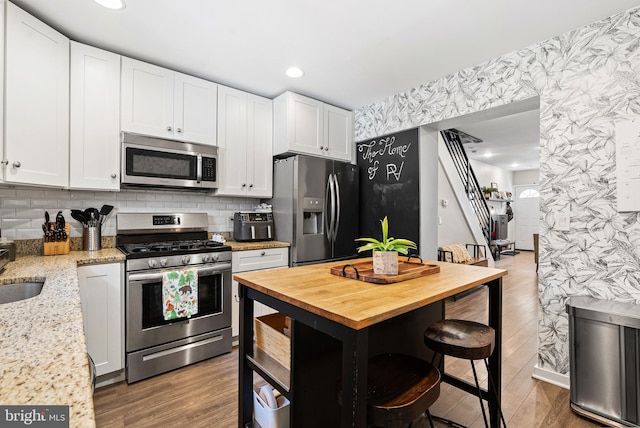 kitchen featuring wooden counters, white cabinetry, stainless steel appliances, and wallpapered walls