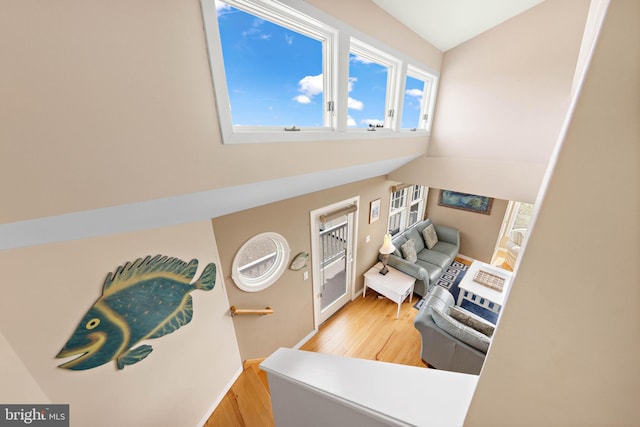 interior space with baseboards, light wood-style flooring, and high vaulted ceiling