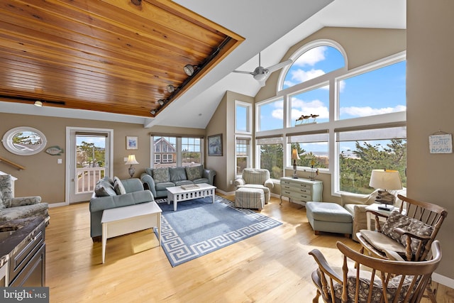 living room with baseboards, a ceiling fan, light wood-type flooring, and high vaulted ceiling