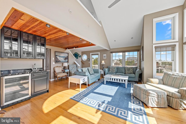 living room featuring indoor wet bar, beverage cooler, ceiling fan, and light wood-style flooring