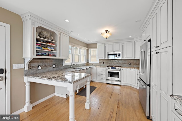 kitchen featuring a sink, light wood finished floors, decorative backsplash, and stainless steel appliances