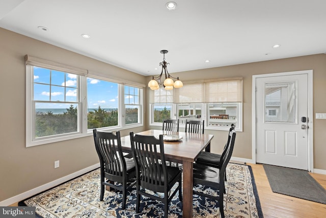 dining space featuring baseboards, recessed lighting, light wood-style flooring, and an inviting chandelier
